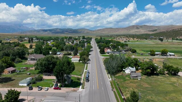 Aerial time lapse rural city main street Utah. Farming community agricultural economy. Spring summer weather mountain valley green agriculture field. Homes, barns and buildings.