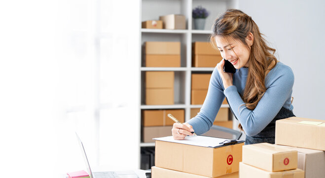 Startup small business entrepreneur SME or freelance Asian woman using a mobile phone with box, Young success Asian woman with online marketing packaging box and delivery, SME concept.