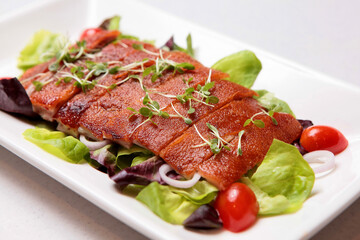 traditional chinese crispy grilled bbq whole suckling pig meat with salad green decoration on white...