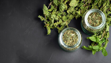 Dried peppermint in a glass jar and a bunch of fresh mint, medicine herb on black background, top...