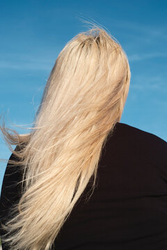 風で髪が靡く金髪の女性の後ろ姿
