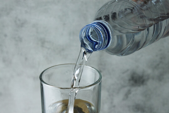 pouring water from bottle into glass on grey and texture background