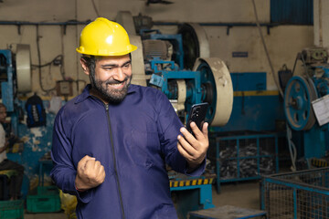 Indian labor giving winning gesture after looking in smartphone