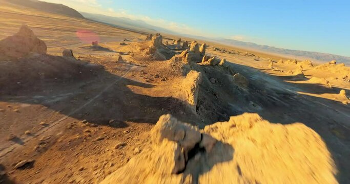 FPV drone captures the surreal beauty of Trona Pinnacles bathed in the warm hues of the golden hour. Unique landscape and cinematic appeal.