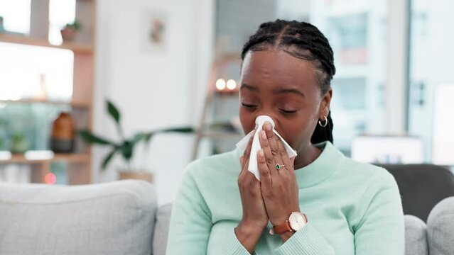 Sneeze, blowing nose and sick black woman with tissue on a sofa for allergies, hay fever or viral infection at home. Sneezing, bacteria and African lady with congestion, covid or flu in living room