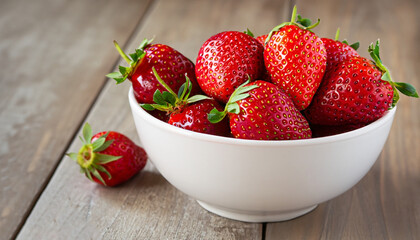 Fresh strawberries in a white porcelain bowl on wooden table in rustic style, selective focus