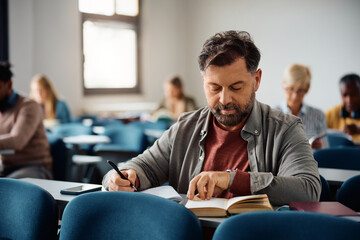 Mature man studying while attending adult education training class in classroom.