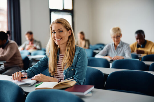 Happy mid adult woman attending educational course in classroom and looking at camera.