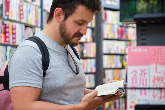 Latin tourist trying to read a comic written in Japanese at a comic book store in Tokyo.