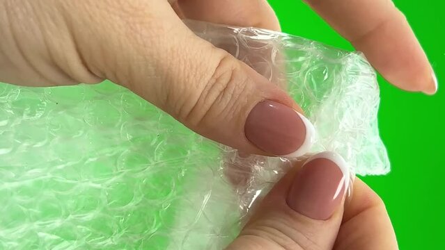 Relieve stress air bubble wrap hands of woman presses that burst soothing nerves on green background chroma key adults Hands of middle-aged play 
