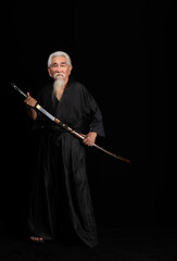 Senior Japanese samurai with katana sword on black background, studio shot