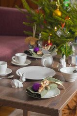 Coffee serving with white tableware for Christmas on a table near a dark pink sofa. Christmas concept, table setting