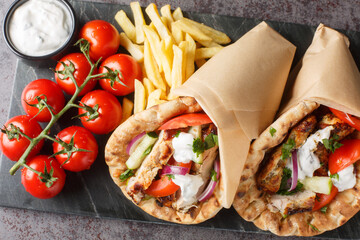 Greek fast food gyros with chicken, tomatoes, cucumbers and onions served with tzatziki sauce and...