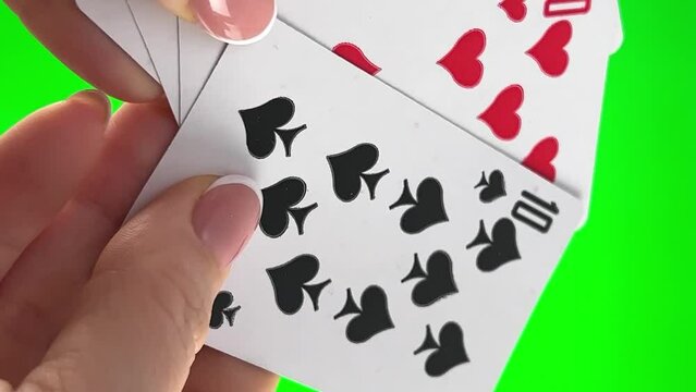 Hand holding four dozens on green background close-up Tens in cards female hands with french manicure. woman sorts through cards, examines folds and spreads out like fan four cards left of same suit