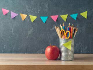 Back to school background with pencils and apple on wooden table over blackboard  background