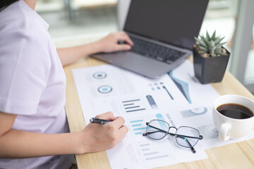 A business woman typing laptop for online working while sitting at her home. freelancer working in everywhere. Flat lay with blank copy space. business office background. Financial data analyzing.