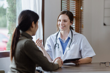 female doctor with female patient and telling advices sitting at workplace in clinic office, Healthcare and medical concept.  