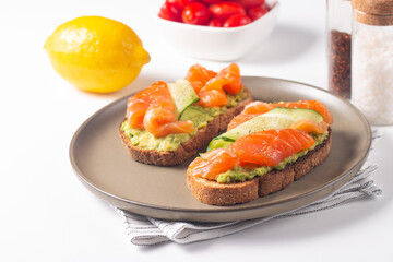 Two tasty open salmon sandwiches with avocado and cucumber. Morning healthy breakfast. Top view.