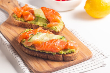 Two tasty open salmon sandwiches with avocado and cucumber. Morning healthy breakfast. Top view.
