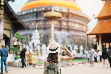 Fototapeta na wymiar Young asian woman traveler in white dress with hat and bag traveling in Wat Phra That Lampang Luang, Tourist visit at Lampang, Thailand.. Asia Travel, Vacation and summer holiday concept