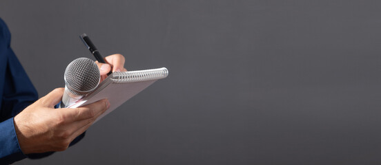 Caucasian journalist holding microphone, notepad and pen.