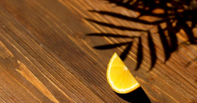 Mockup wooden brown background, orange slice and palm shade