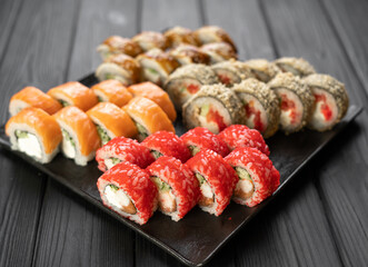 Sushi set on black background, variety of sushi rolls on black stone, sushi menu concept