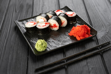 Sushi maki on black stone board with chopsticks on dark background, top view