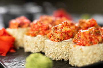 Close Up on serve baked sushi rolls with eel and tobiko caviar on black slate board