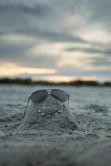 Funny face made out of sand on the beach wearing sunglasses - 632892420