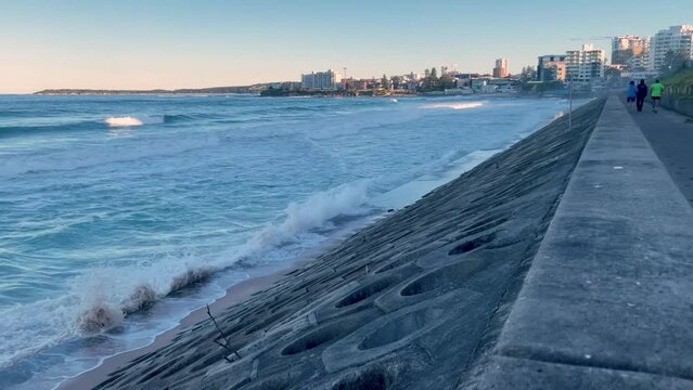 HD Video- Waves crashing on the sea wall at North Cronulla Beach, Sydney, Australia. Due to coastal erosion and following a storm (June 2022) sand was ripped from the beach and ocean reached sea-wall.