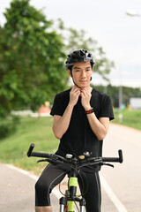 Fototapeta na wymiar Young asian man wearing protective helmet, riding bicycle in the countryside. Sport and active lifestyle concept