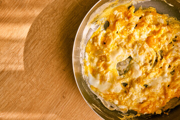 Homemade omelette with cheese on a wooden kitchen table.