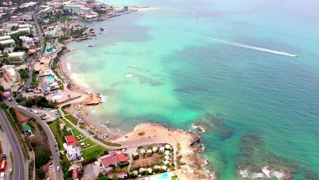 Static slow-motion aerial view of the coastline and turquoise sea of the city of Hersonissos on the Greek island of Crete.
