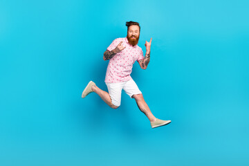 Full body profile photo of overjoyed eccentric man jumping fingers demonstrate heavy metal symbol...