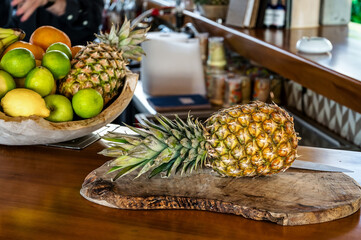Unsliced pineapple resting on a rustic wooden board, a perfect embodiment of the bar concept. Close-up photo, blurred background. 