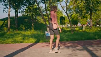 woman dressed activewear going to the yoga class walking in summer city park