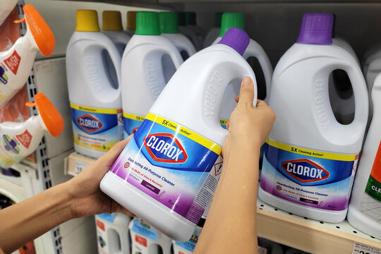 PENANG, MALAYSIA - 11 JULY 2023: Close up female hand holding a bottles of Clorox Bleach in grocery store. Clorox is an American Company founded in 1913.