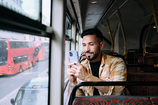 Young man taking photos from a bus in London