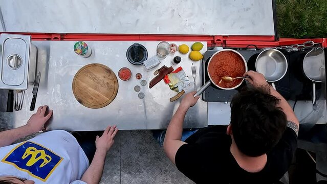 Top view image. Men cooking outdoors, preparing tomato sauce for meat. Outdoor kitchen. Culinary. Concept of food, cuisine, hobby, taste, weekend activity, street cookery