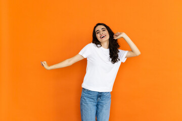 Attractive cheerful woman rejoicing having fun isolated over bright orange color background