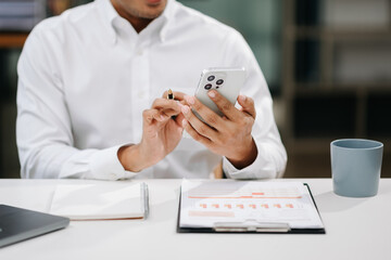 Asian business man documents on office desk with laptop and smart phone and graph business diagram...
