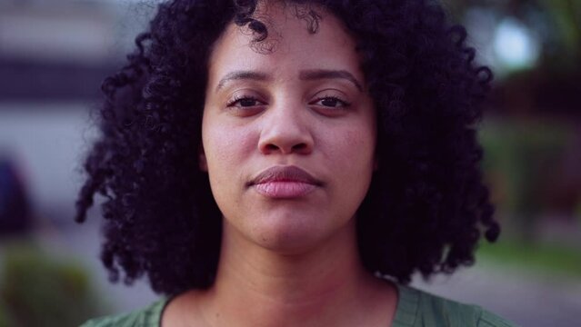 A Brazilian black young woman portrait face closeup standing outside looking at camera. African American adult girl female person