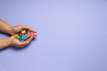 Multicolored puzzle pieces in hands on a light background, place for text. World autism day concept