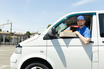 A smiling courier carries parcels by car
