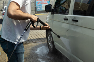 Fototapeta na wymiar A man washes a car at a self-service car wash