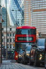 Fototapeta premium Cars and red doubledecker in row on road. Modern office buildings in financial district. View of busy street in city of London.