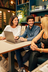 Group of focused young multiracial colleagues gathering around table with laptop and discussing...