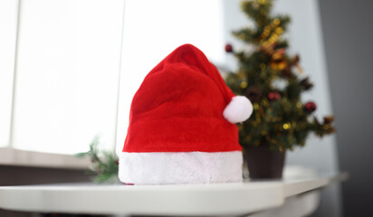 Santa claus hat standing near christmas tree closeup. Christmas holidays concept