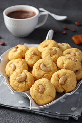 Homemade carrot cookies with cashews, peanuts and dried apricots and a cup of coffee on gray background, Closeup